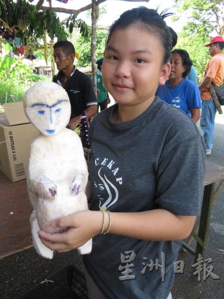 甘榜女孩手持一个以棕榈树干雕刻而成的猴子。