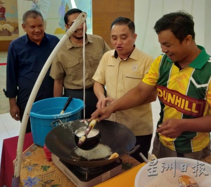 黄瑞林（右二）在稻米博物馆职员的指导下，学习如何制作米饼。左起为哈斯努和莫哈末法克鲁拉兹。（图：星洲日报）