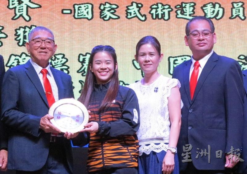 勇夺世界武术锦标赛1金2银的陈昌敏（左二）获得福建会馆表扬，从主席史亚狮手中接过贺盾，右一及二为其父母陈宝全夫妇。