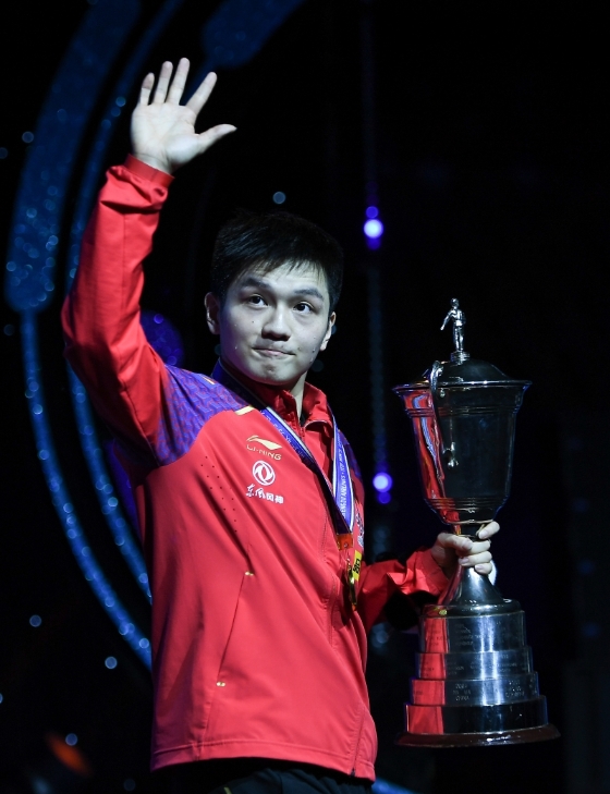 樊振东在男子乒乓世界杯决赛4比2打败张本智和，生涯第3次夺得赛会冠军。图为樊振东赛后手捧冠军奖杯向现场观众致谢。（新华社照片）