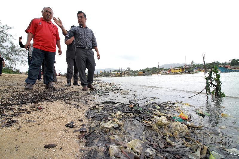 沙鲁丁(右一)帶領媒體巡視沙灘上的垃圾污染情況。