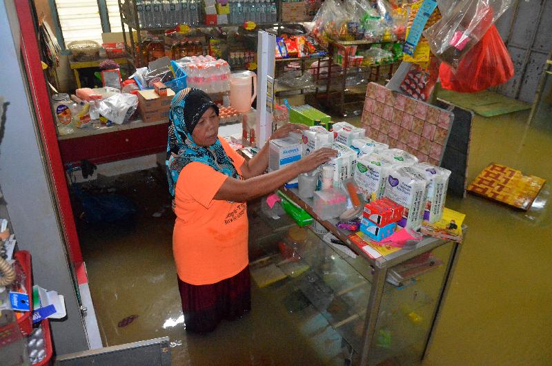 位于乌鲁登嘉楼甘榜巴雅勿刹的杂货店被水淹，店家把货物放到架子上以免损毁。
