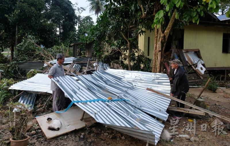 勿述甘榜拉的村民莫哈末沙礼（左）在邻居阿都拉欣的协助下，把大水冲毁的屋顶搬走。