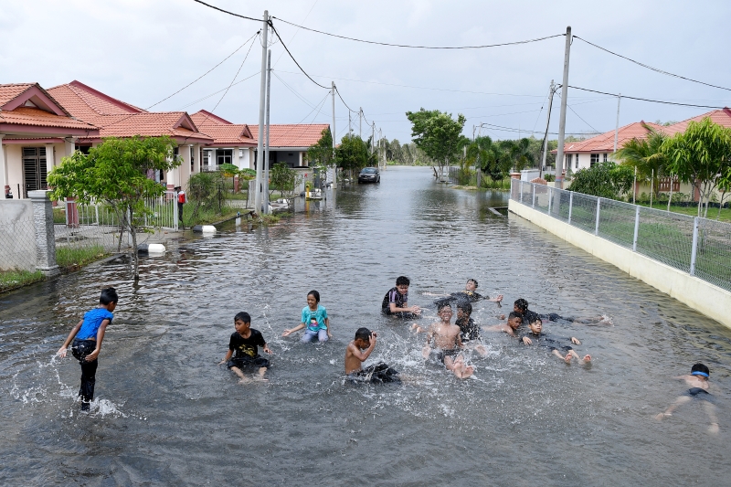 瓜拉尼鲁斯其中一个受到水灾影响的花园住宅区道路积水，孩童们乘机戏水玩乐。
