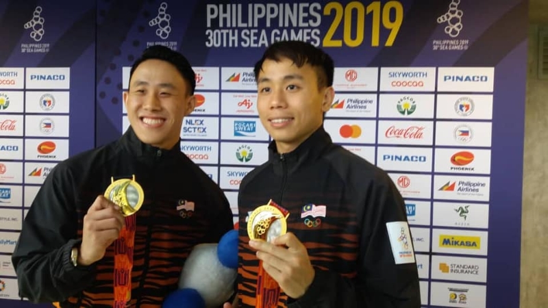 黄兹樑（左）和周贻蔚在男子双人3公尺跳板跳出金牌，两人赛后举起奖牌合照。（Majlis Sukan Negara脸书照片）