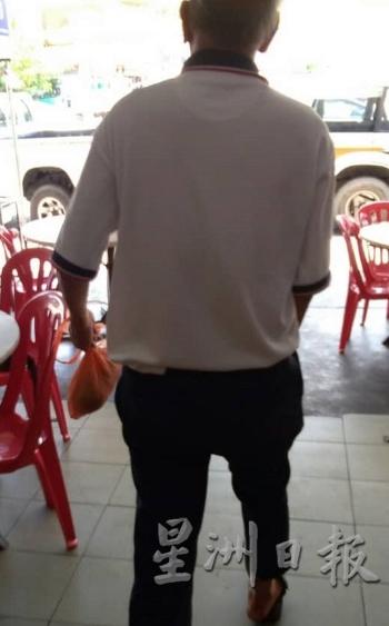 被狗咬伤的王茂民在洗净脚踝伤口后,负伤步出茶室准备前往诊所接受治疗。(图:星洲日报)