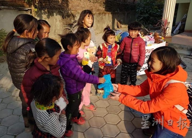 黄婕妤（右一）去年到尼泊尔时，为当地孩子献上募集的旧玩具，孩子们都相当快乐。（图：星洲日报）