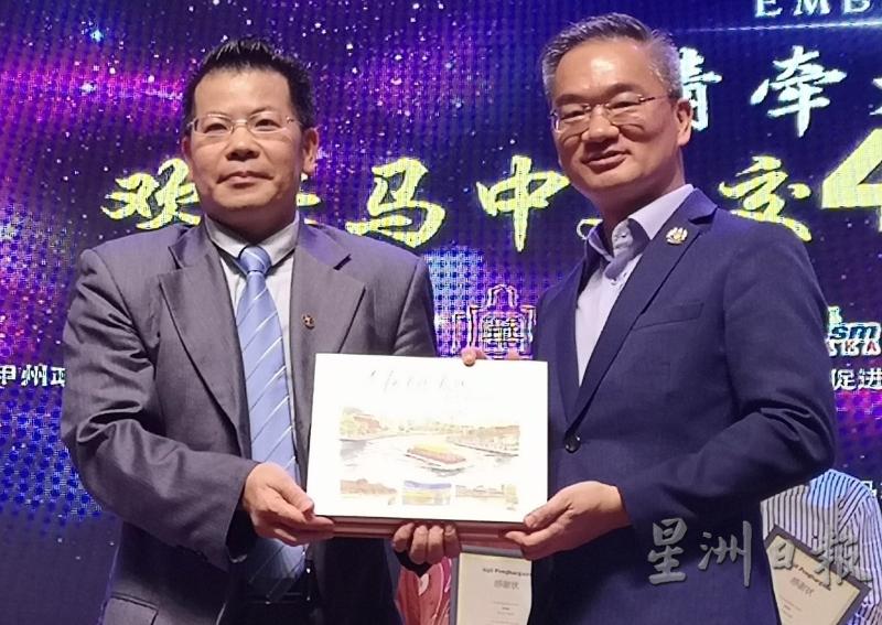 邱培栋（右）赠送纪念品给中国江门市侨委会副主席余释权。（图：星洲日报）