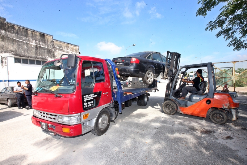 沙亚南市政厅利用起重机将废车举起，置放在拖车上，以方便将其拖走。