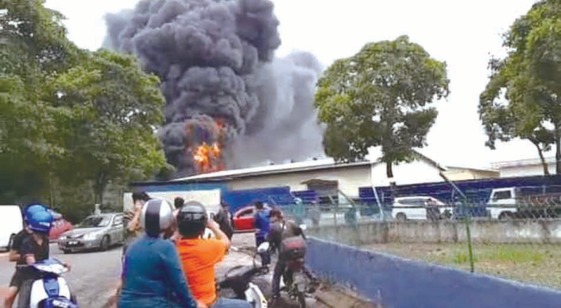 工厂失火冒出浓浓烟火,民众驻
足围观。(图片民众提供)