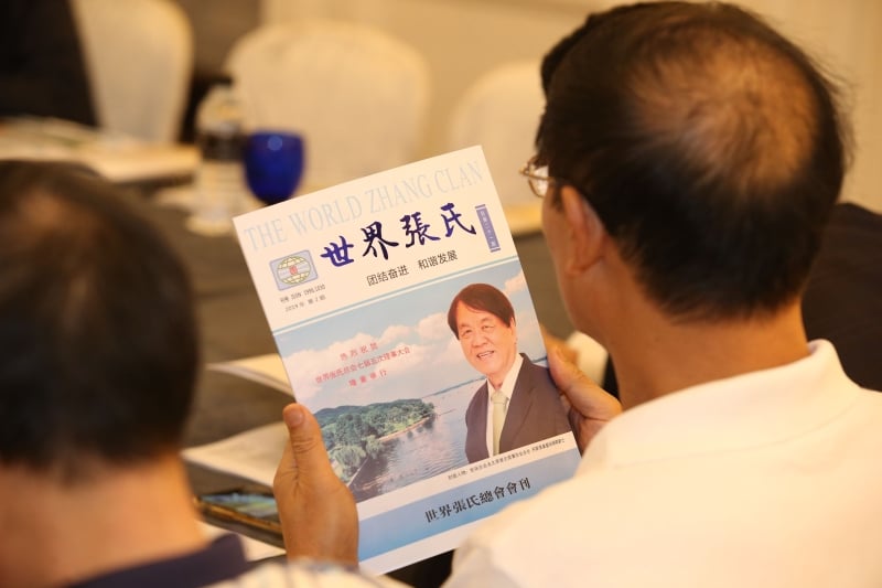 会员正阅读世界张氏总会会刊，本期封面人物为世张总会永久荣誉主席兼创会会长，同时也是世华媒体有限公司荣誉主席的丹斯里张晓卿爵士。