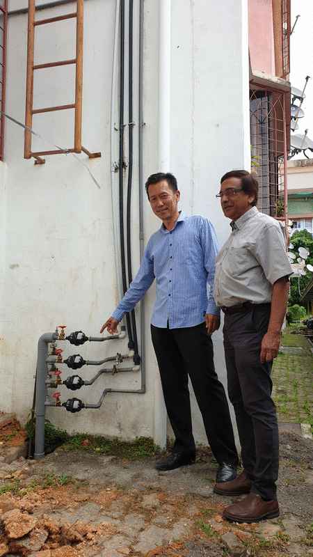 江伟立（左）和拉南德拉展示通往住户的新水錶和新水管。