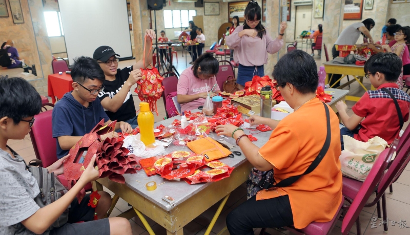 今年庙会的亲子红包封手工制作赛吸引多个家庭参赛，只见父母和孩子合力完成作品，过程温馨愉快。（图：星洲日报） 
