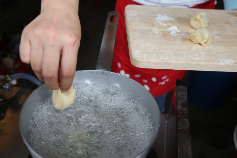 清水煮至沸腾后，将饺子放入锅中，并采用“三起三落”的煮法，待饺子煮熟后，将其捞起。