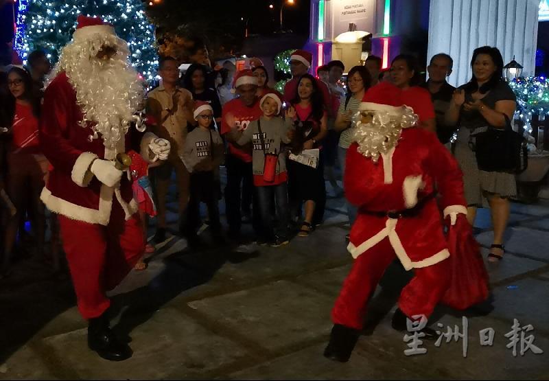 2个“圣诞老人”在广场前载歌载舞，散播了欢乐的气氛。
