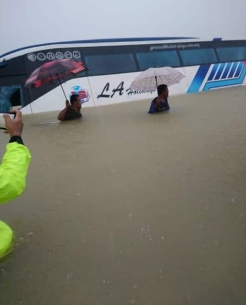 一辆长途巴士被困在高及成人胸部的大水中，乘客由拯救人员救出才脱险。（图取自网络）