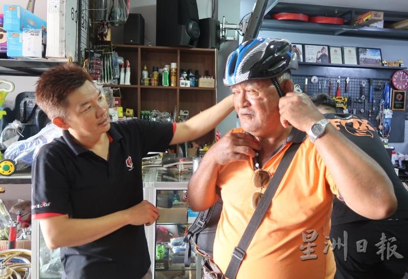 许俊平（左）指导顾客戴上安全帽。（图：星洲日报）
