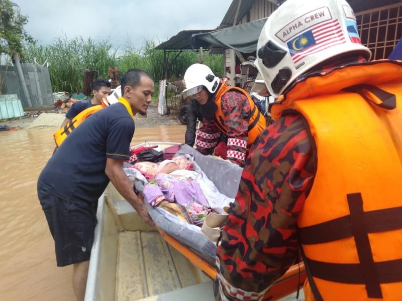 居民协助消拯人员将受困人士移到救灾小艇上。（图：柔州消拯局总部提供）