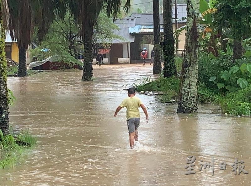 淋得满身湿透的孩童，穿著拖鞋涉水回到住所。（图：星洲日报）