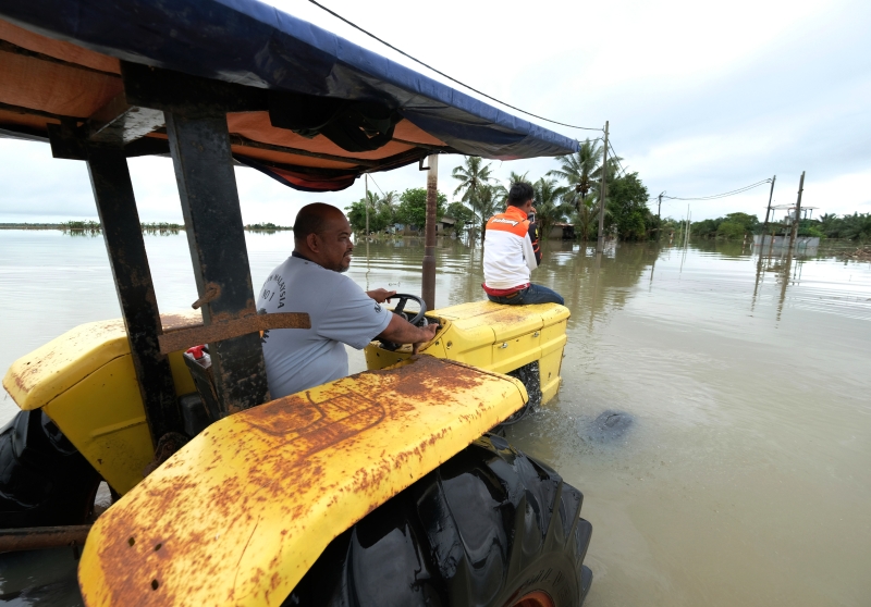 由于处处淹水，水位及腰，云冰甘榜古尼亚居民诺里山驾驶拖拉机回家，以便为退避疏散中心的家人拿取衣服供替换。