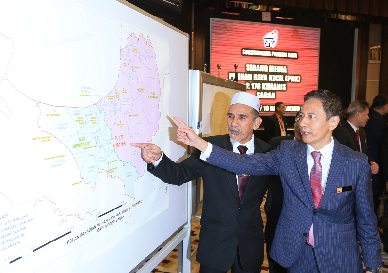阿兹哈（右）和金马利国席补选选举官祖巴利展示选区分布图。