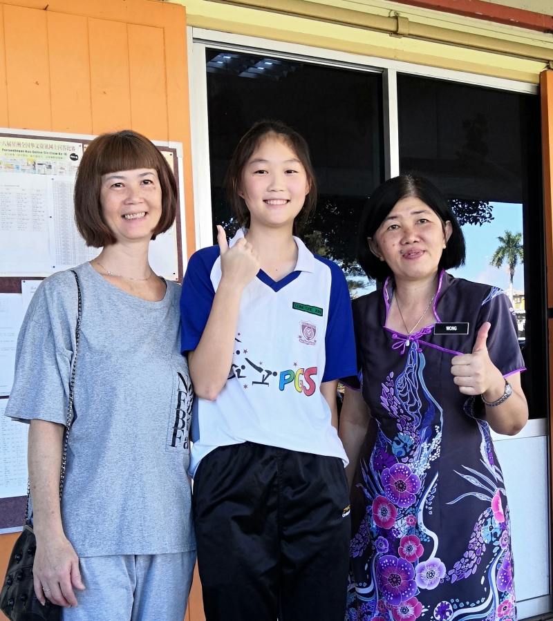 霹雳女中排球队队员林丽心（中）被选中进入吉隆坡武吉加里尔国家体育训练中心受训，妈妈廖玉霞（左）和校长黄淑娟引以为傲。