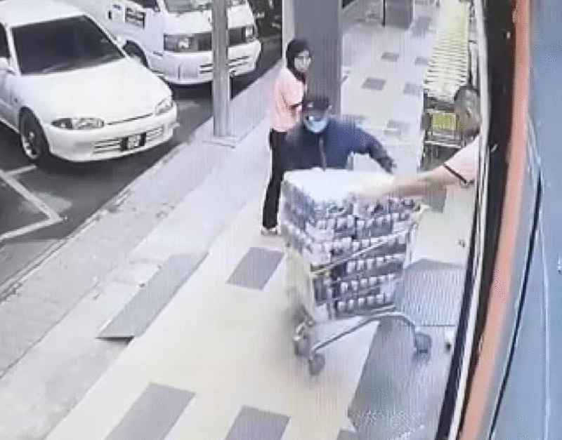口罩男推购物车离开时，相信是超市职员的手（右）帮忙他推购物车。 