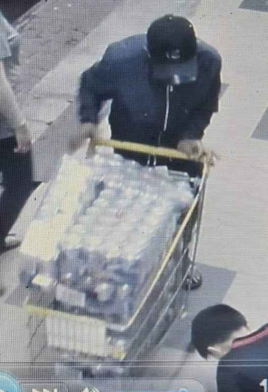 闭路电视拍摄得一名男子推了放满啤酒的购物车。 