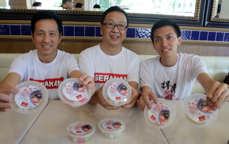 胡栋强（左起）、刘华才与槟州民青团委员锺伟振向槟州民众呈献有团结意义的汤圆。