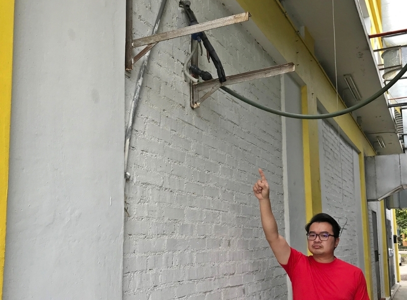 王振宏指店屋外墙的冷气压缩机失窃后，仅留下遭匪剪断的电缆。（图：星洲日报）