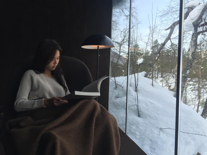 林绿透过住宿内的玻璃窗，在欣赏窗外美景下阅读，知性味十足。