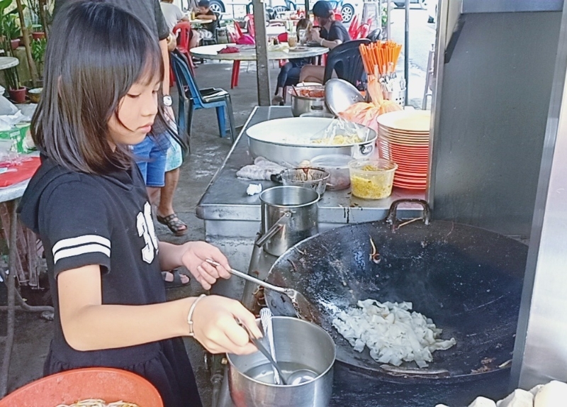 年仅8岁的庄凯惠，已能拿起锅铲炒粿条。（图：星洲日报）