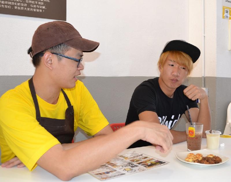 郑旐亓（左）向表弟覃祥宗推介自己烘焙的古奇曲饼。
