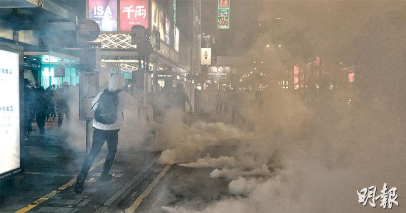 今年香港的平安夜不太平安。昨晚入夜后，警方与市民在尖沙嘴爆发冲突，其中警方在弥敦道近半岛酒店发射多枚催泪弹驱散人群，霎时间弥敦道烟雾弥漫，多名途人慌忙走避。（图：明报·冯凯键摄）
