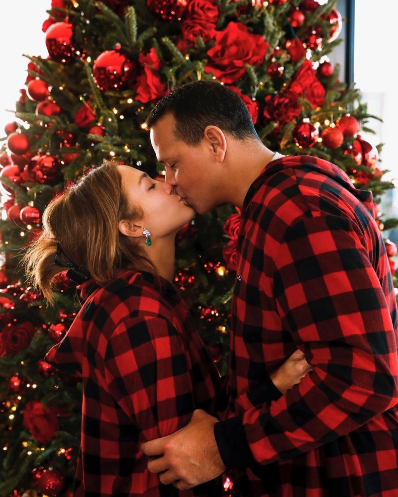 珍妮花洛庇丝在IG晒出与未婚夫A-Rod身穿同款红格子连衣帽，在圣诞树下甜蜜亲吻的放闪照，祝粉丝圣诞节快乐。