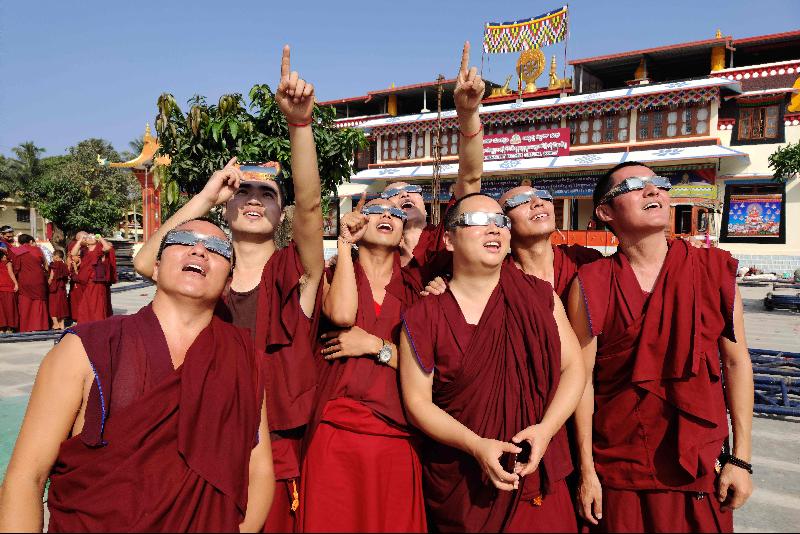 在印度南部卡纳塔克邦的流亡藏人聚居地，当地甘丹寺的一群喇嘛戴上太阳滤镜，观看日食奇景。（图：法新社）