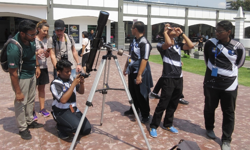 玛拉工艺大学打巴分校天文学学会学生置放一个望远镜观看日食，吸引洋人准备一齐观看。