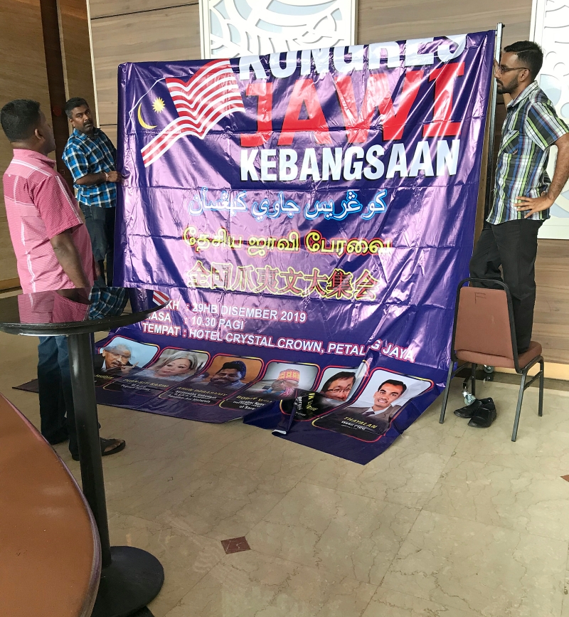 工作人员准备挂上全国爪夷文大会的巨型海报。