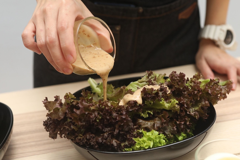 将生菜铺在盘内，加入芝麻沙拉酱。