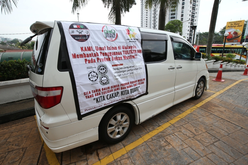 休旅车外张挂显眼的标语直幅，内容为“我们伊斯兰信徒反对非穆斯林产品使用爪夷文”。