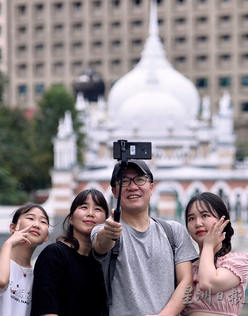 政府延长中国和印度游客15天免签证措施一年，以吸引两国游客前来。图为中国游客周六在吉隆坡生命之河河畔自拍。