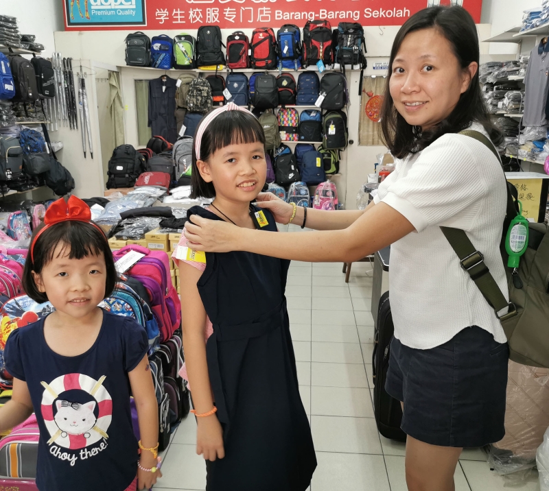 张瑜玹（右）为女儿添购校服，至于白鞋则尽量穿到校鞋白换黑措施实行时才买黑鞋。