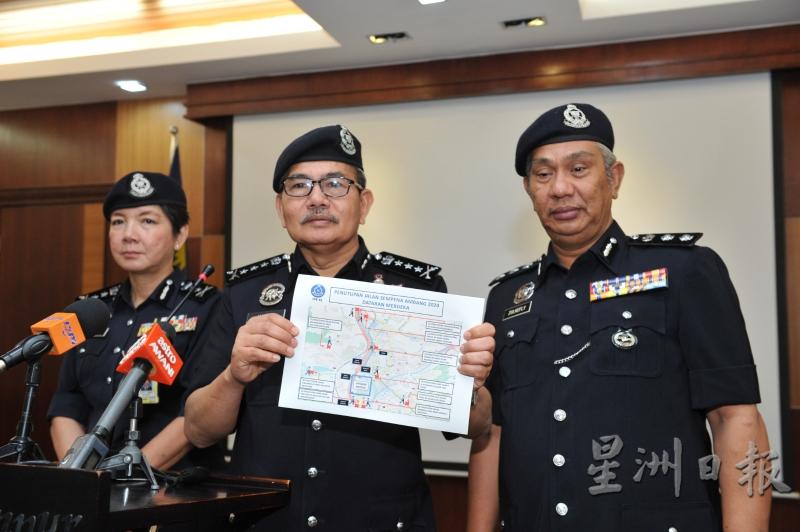 马兹兰（中）向媒体展示警方将分阶段封锁的路段图。左为吉隆坡副总警长拿督杨丽珠，右为吉隆坡交通调查与执法组主任祖基菲里助理总监。