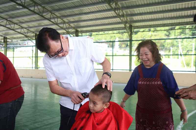 潘明丰（左）亲自为学生理髮，展示亲民的一面。