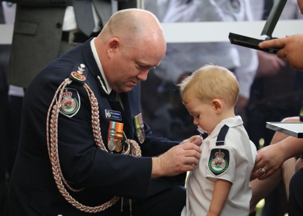 吃着奶嘴的哈维（右）接受父亲的英勇勋章。（互联网照片）