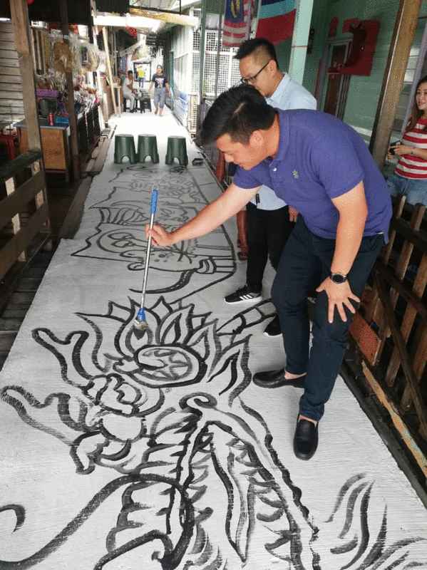 邱文正日前到渔船街，拿起画笔，象征式地为《12生肖》地画上的龙点睛。