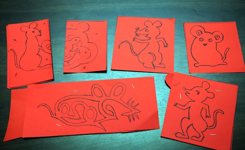 （一）在对折了一半或叠在一起的两张红纸上，画出自己要剪的老鼠图案。