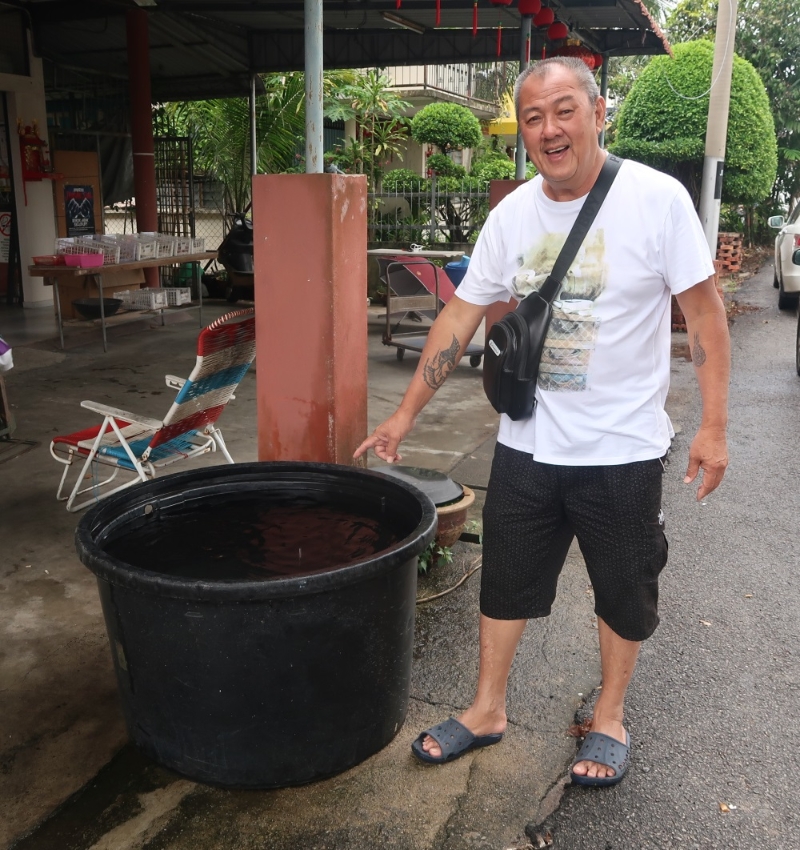郑天生在杂货店前设置大水桶来收集雨水。