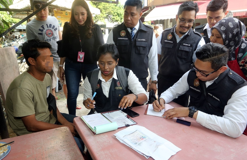 一名孟加拉籍外劳（前排左一）被发现在食肆内吸烟，接获执法人员开出的罚单。