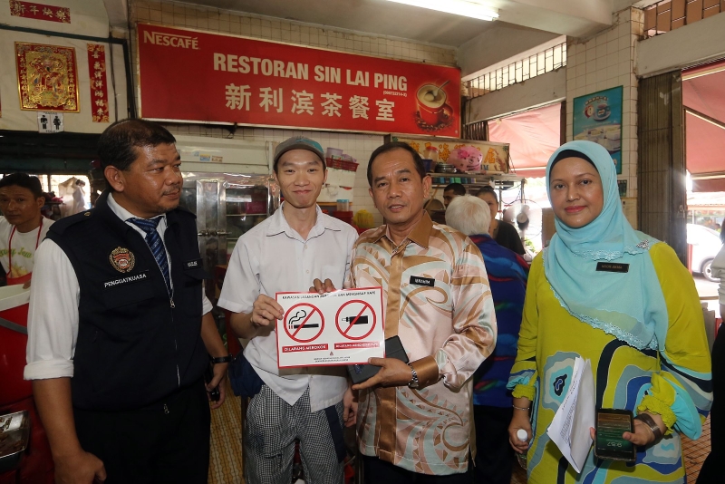 吉隆坡市政局执行总监拿督依布拉欣（右二）移交禁止吸烟及电子烟的告示牌予食肆业者。右一为诺阿玛。
